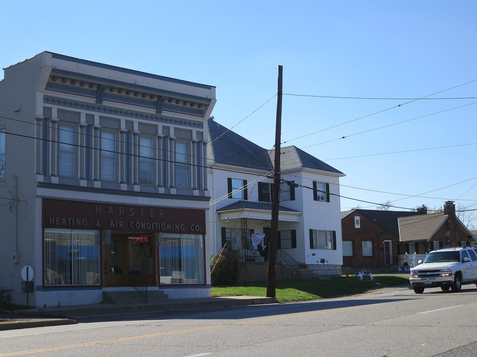 A storefront and houses along Gravois Road in Affton, Missouri, under a clear sky.